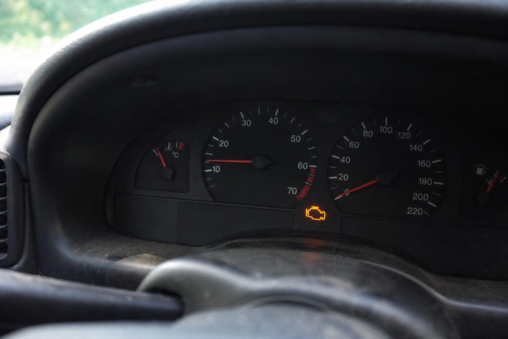 Régebbi autó műszerfala alapjárati motorhibára utaló természetes motorhiba-jelzéssel