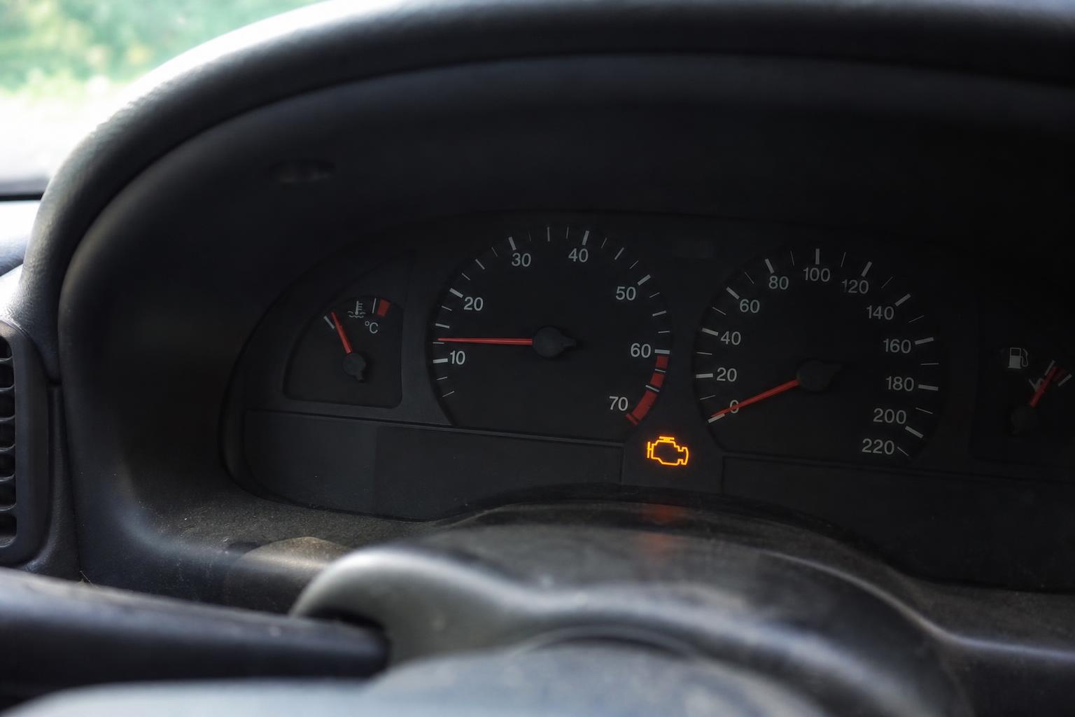 Régebbi autó műszerfala alapjárati motorhibára utaló természetes motorhiba-jelzéssel