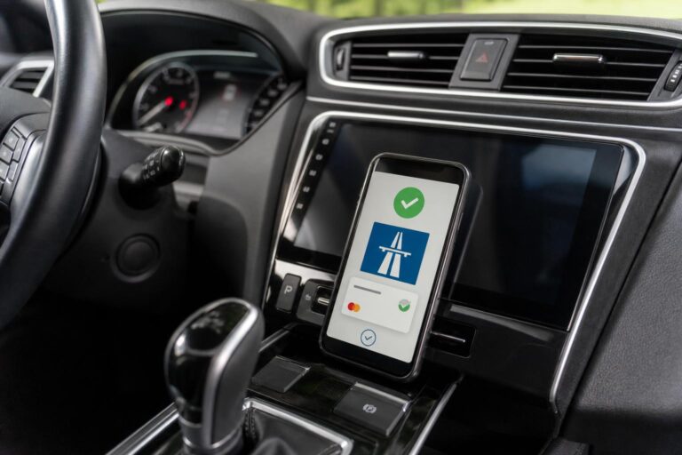 Autópálya-matrica online vásárlását visszaigazoló telefon egy autó belső terében
