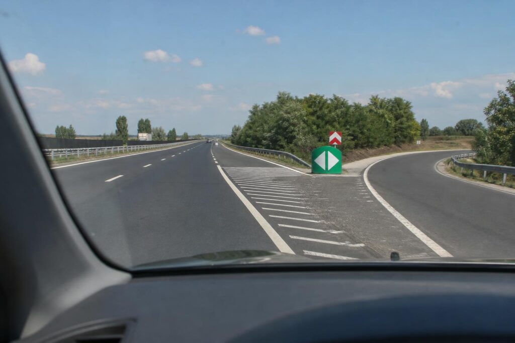 Autó halad tovább az autópályán egy eltévesztett lehajtó után, a kijáratot jelző táblával