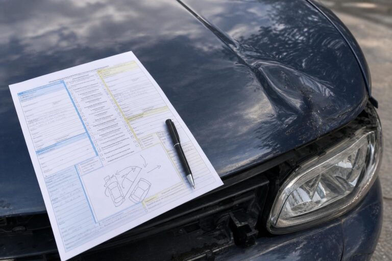 Baleseti bejelentő kitöltése egy koccanás után, sérült autó motorháztetején