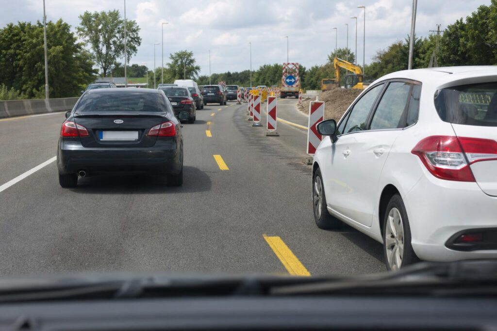 Két autó váltakozva sorol be egy útépítés miatt megszűnő sávból a továbbhaladó sávba