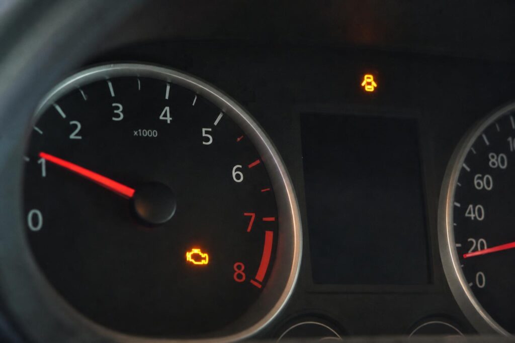 Autó műszerfalának közeli képe világító sárga check engine motorhiba-jelzéssel