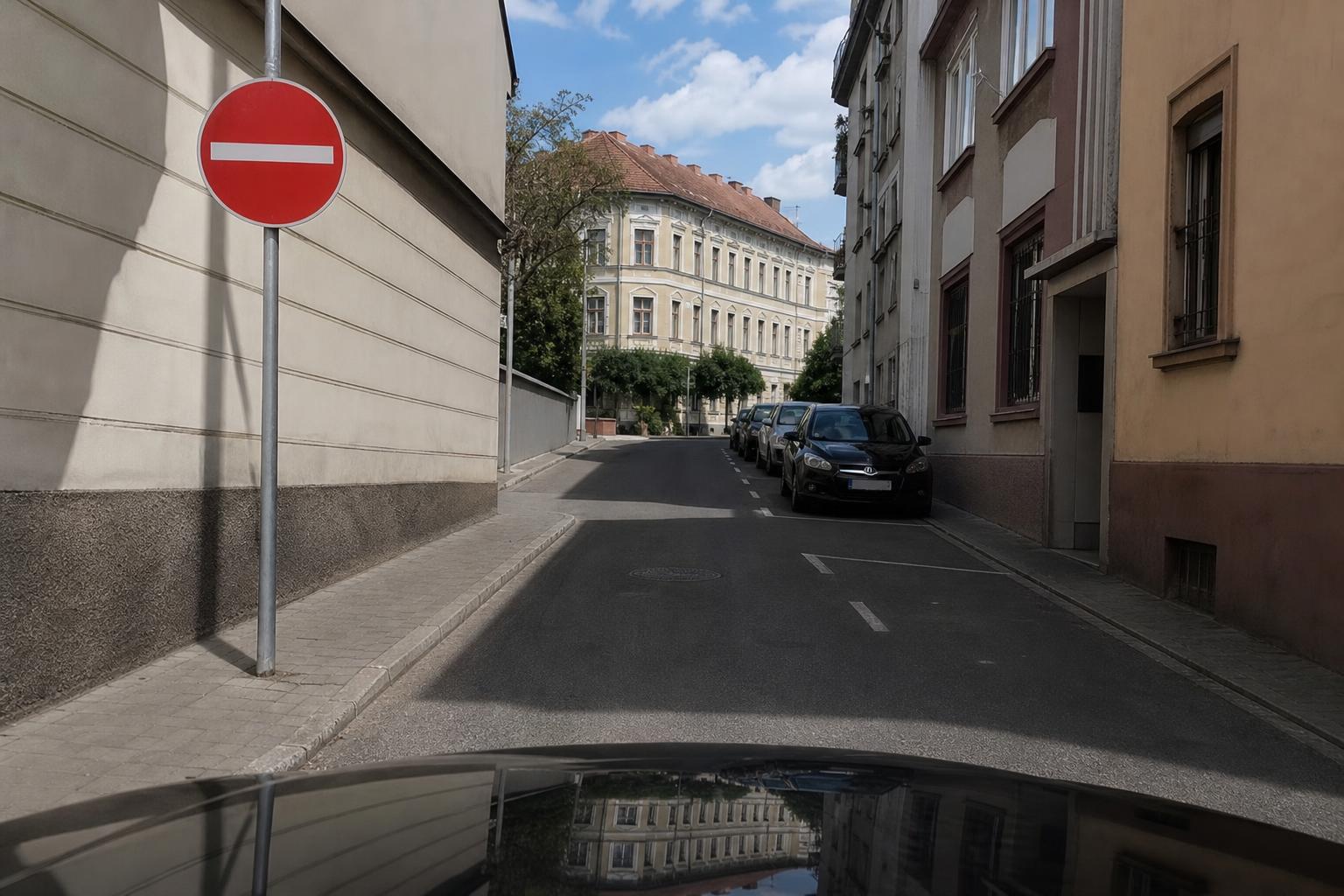 Autó érkezik egy egyirányú utca tiltott bejáratához, jól látható Behajtani tilos táblával