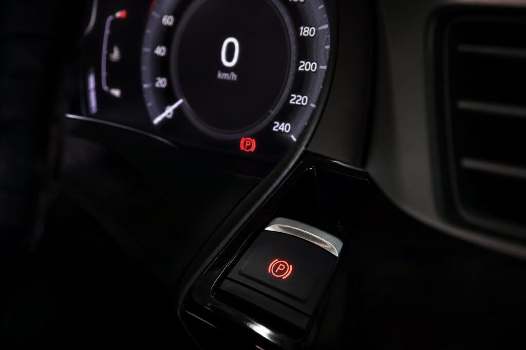 Autó műszerfala piros elektromos kézifék-hibajelzéssel és a rögzítőfék kapcsolójával