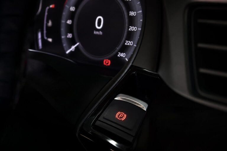 Autó műszerfala piros elektromos kézifék-hibajelzéssel és a rögzítőfék kapcsolójával