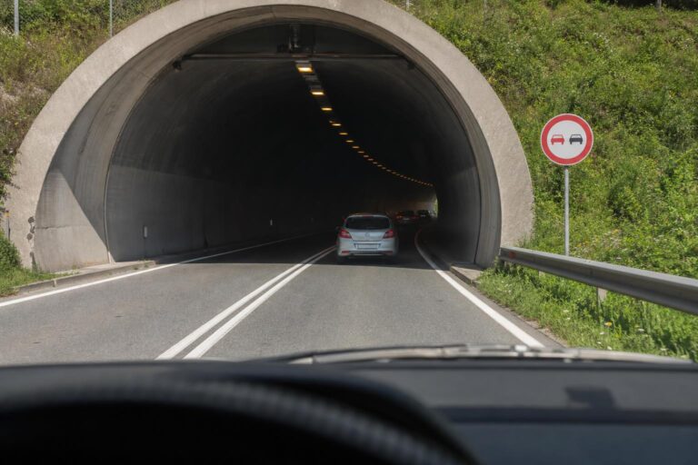 Autó közeledik alagút bejáratához előzést tiltó jelzéssel és jól látható útburkolati jelekkel