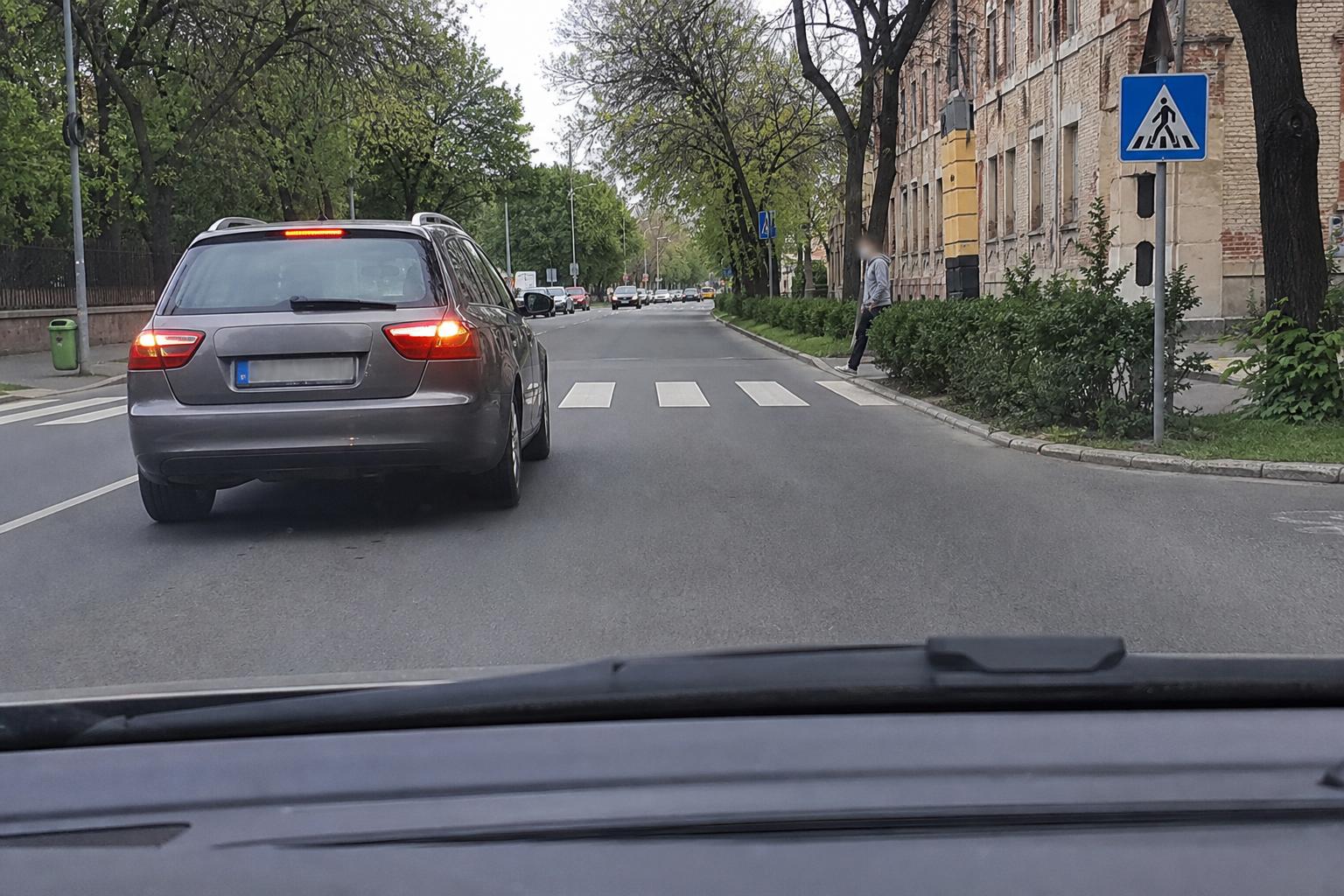 Autó zebra felé közeledik, miközben a szomszédos sávban egy jármű megáll a gyalogos-átkelőhely előtt