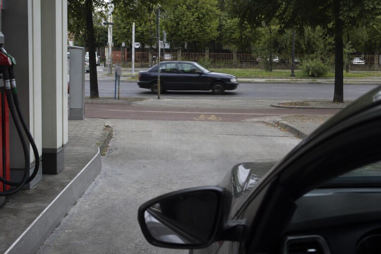 Autó hajt ki egy benzinkút kijáratánál a járdát és kerékpárutat keresztezve