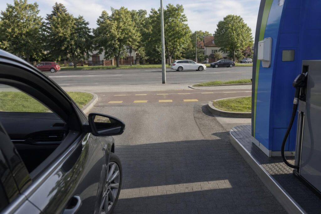 Autó hajt ki óvatosan egy benzinkút kijáratán a járda és a közút keresztezésénél