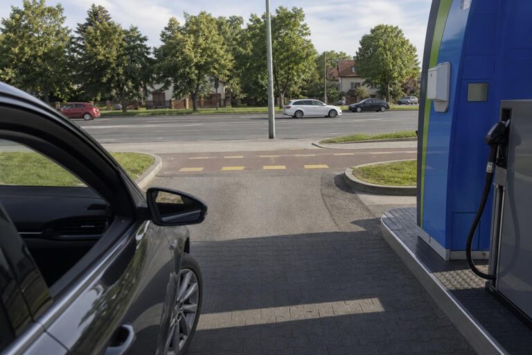 Autó hajt ki óvatosan egy benzinkút kijáratán a járda és a közút keresztezésénél