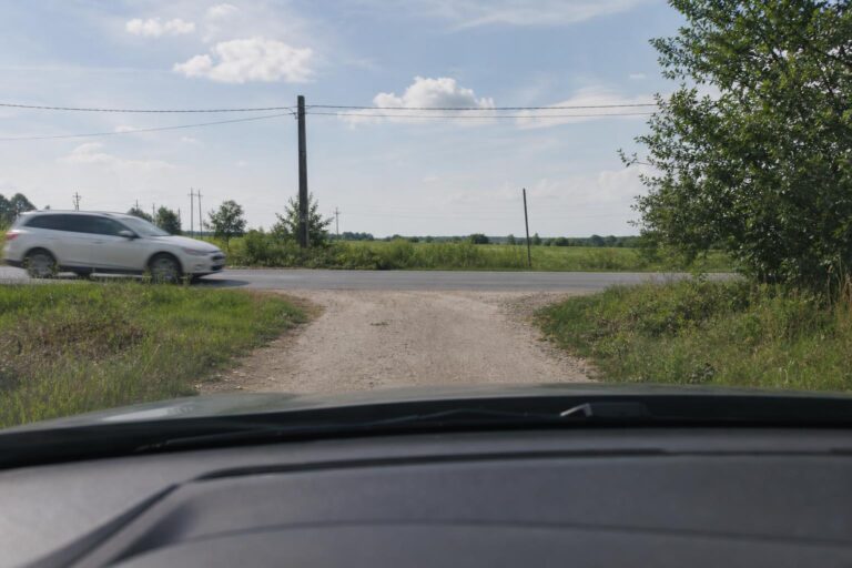 Autó várakozik egy földút és egy szilárd burkolatú út találkozásánál, elsőbbségadásra készülve
