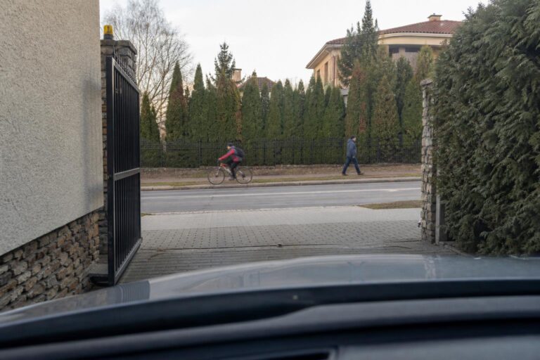 Autó kapubejáróból hajt ki a járda és a közút felé, miközben gyalogos és kerékpáros közeledik