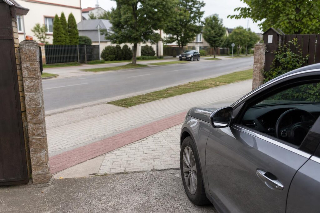 Autó kapubejáróból hajt ki a járdát és kerékpáros útvonalat keresztezve