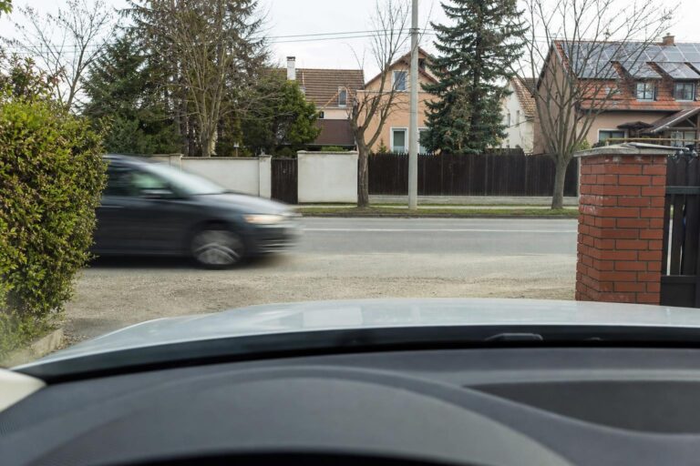 Autó áll egy magánparkoló kijáratánál, mielőtt elsőbbséget adna a közúton haladó járműveknek