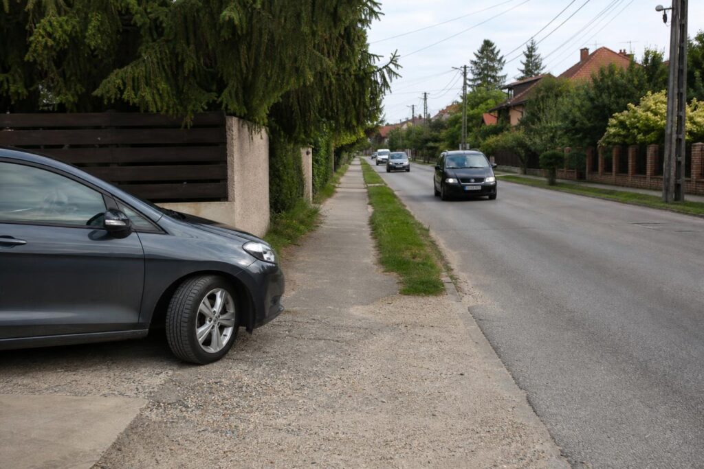 Autó hajt ki egy magánparkolóból a közútra, miközben a járdára és a közeledő forgalomra figyel