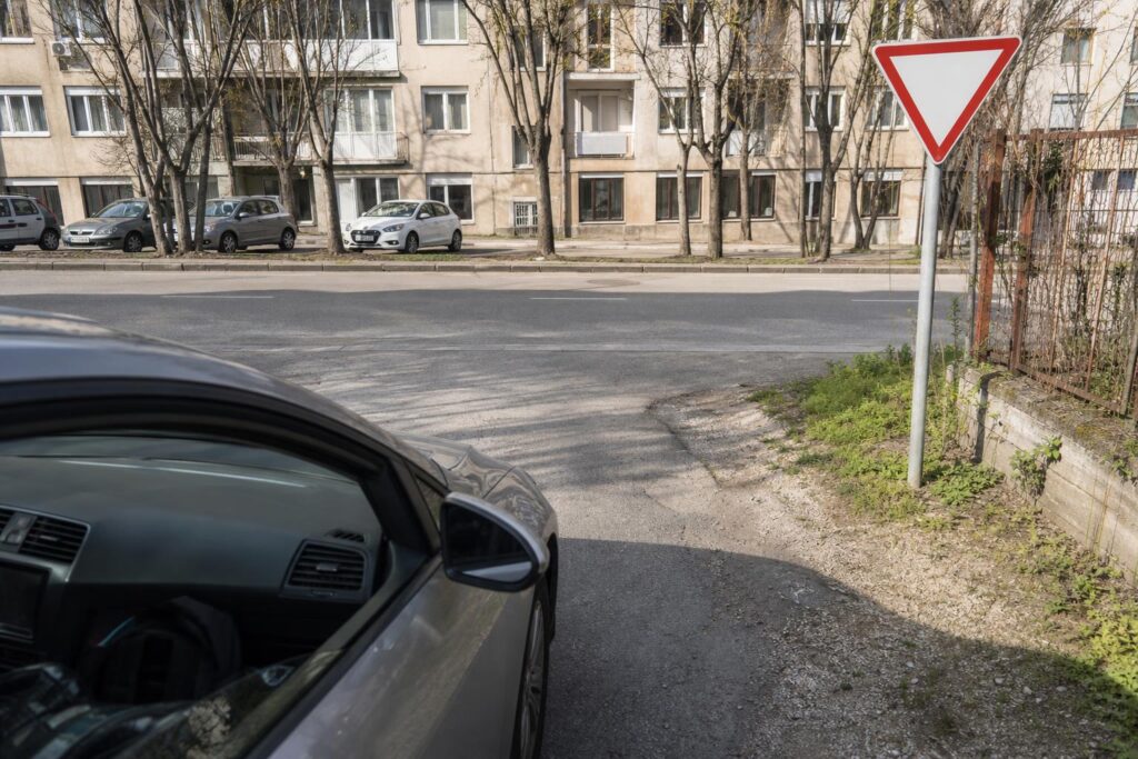 Autó elsőbbségadás kötelező táblánál hajt ki egy szervizútról a közútra