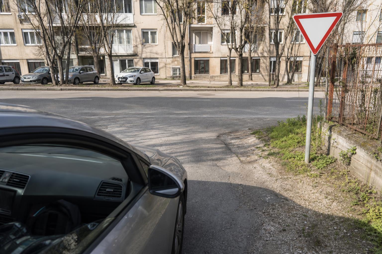 Autó elsőbbségadás kötelező táblánál hajt ki egy szervizútról a közútra