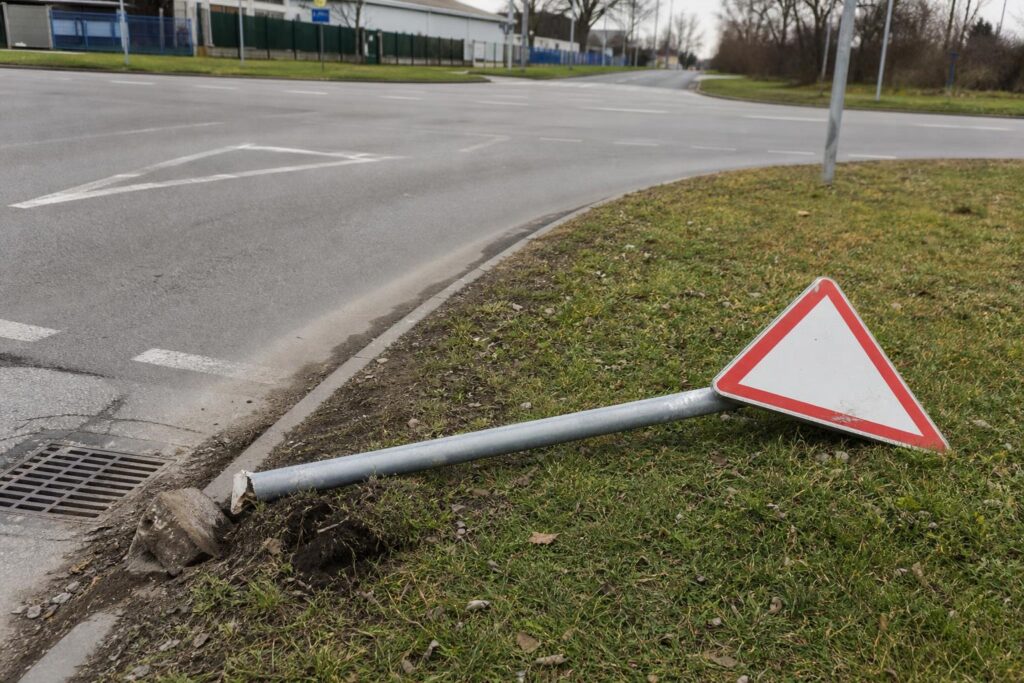 Kidőlt és elfordult elsőbbségadás kötelező tábla egy kereszteződés mellett