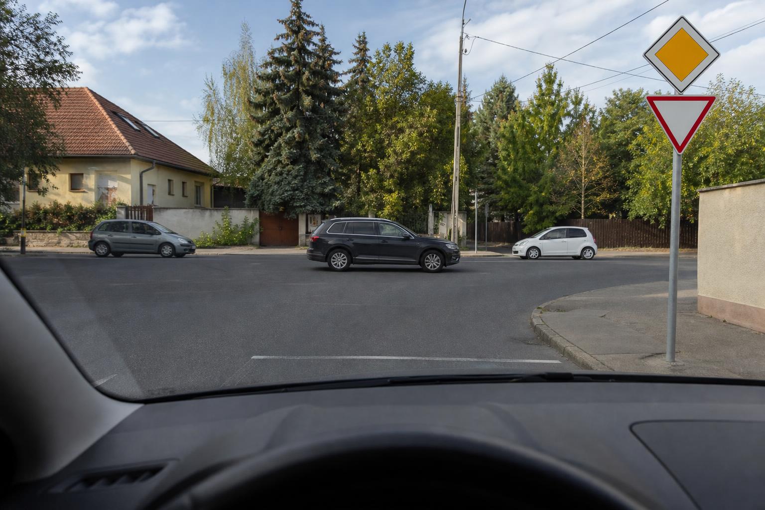 Magyarországi útkereszteződés elsőbbségi táblákkal és különböző irányból érkező autókkal