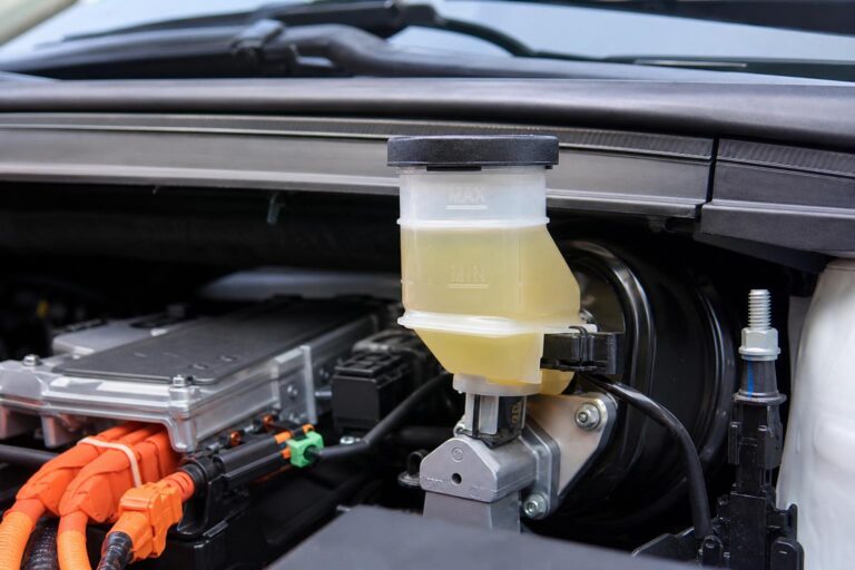 Elektromos autó motorterében látható fékfolyadék-tartály a folyadékszint jelöléseivel