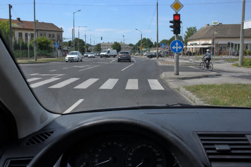 Összetett kereszteződés közlekedési táblákkal, jelzőlámpával, gyalogátkelőhellyel és több járművel