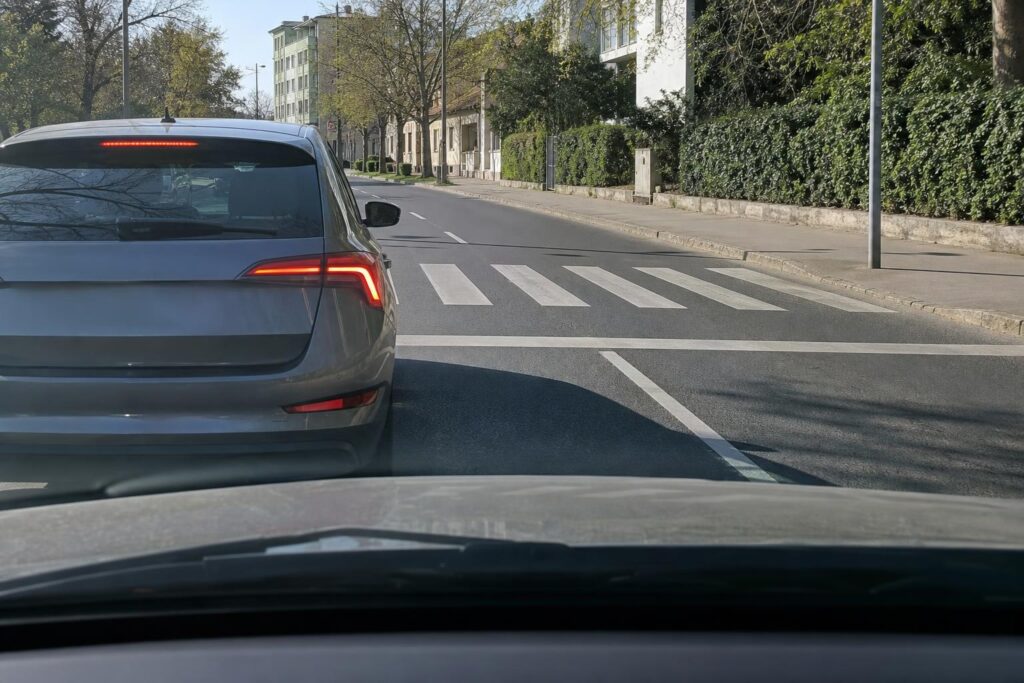 Zebránál megálló autó mellett óvatosan közeledő jármű egy magyarországi úton