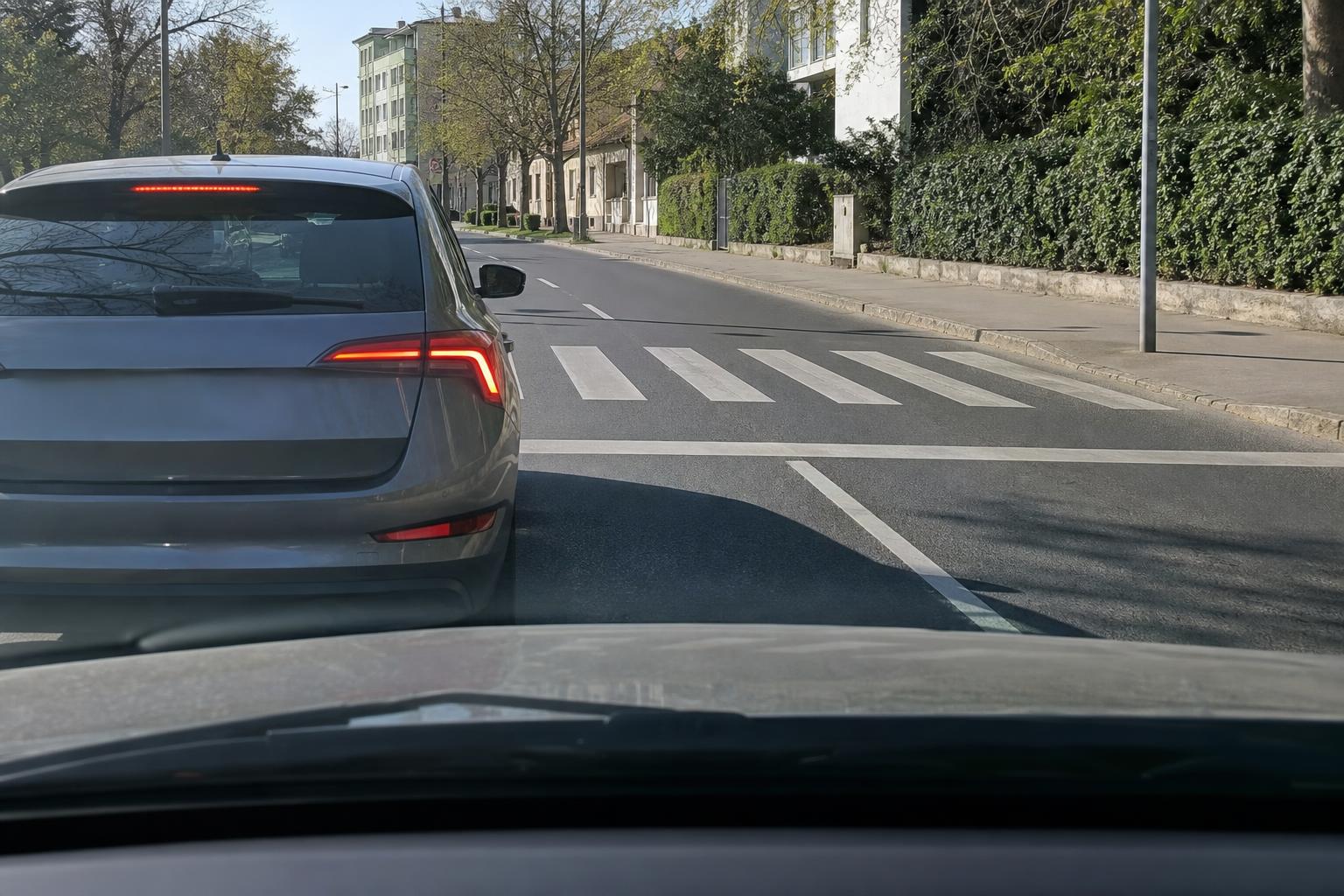 Zebránál megálló autó mellett óvatosan közeledő jármű egy magyarországi úton