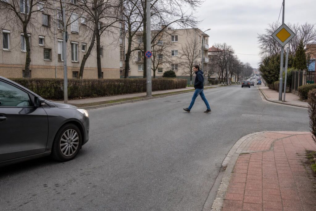 Gyalogos kel át zebra nélküli útkereszteződésben, miközben az autó biztonságos távolságban lassít