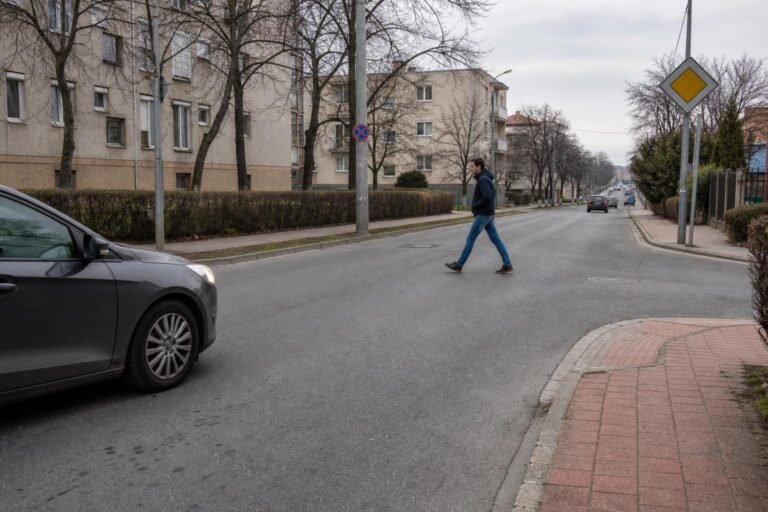 Gyalogos kel át zebra nélküli útkereszteződésben, miközben az autó biztonságos távolságban lassít