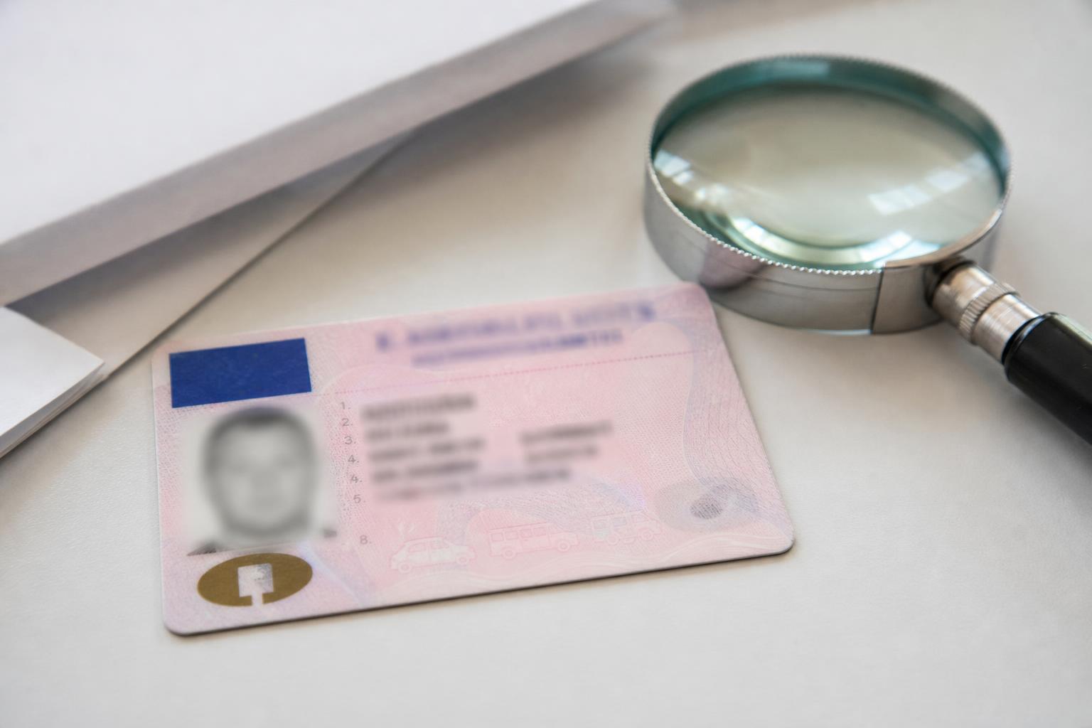 Elmosott adatokat mutató vezetői engedély és nagyító ügyintézéshez előkészítve