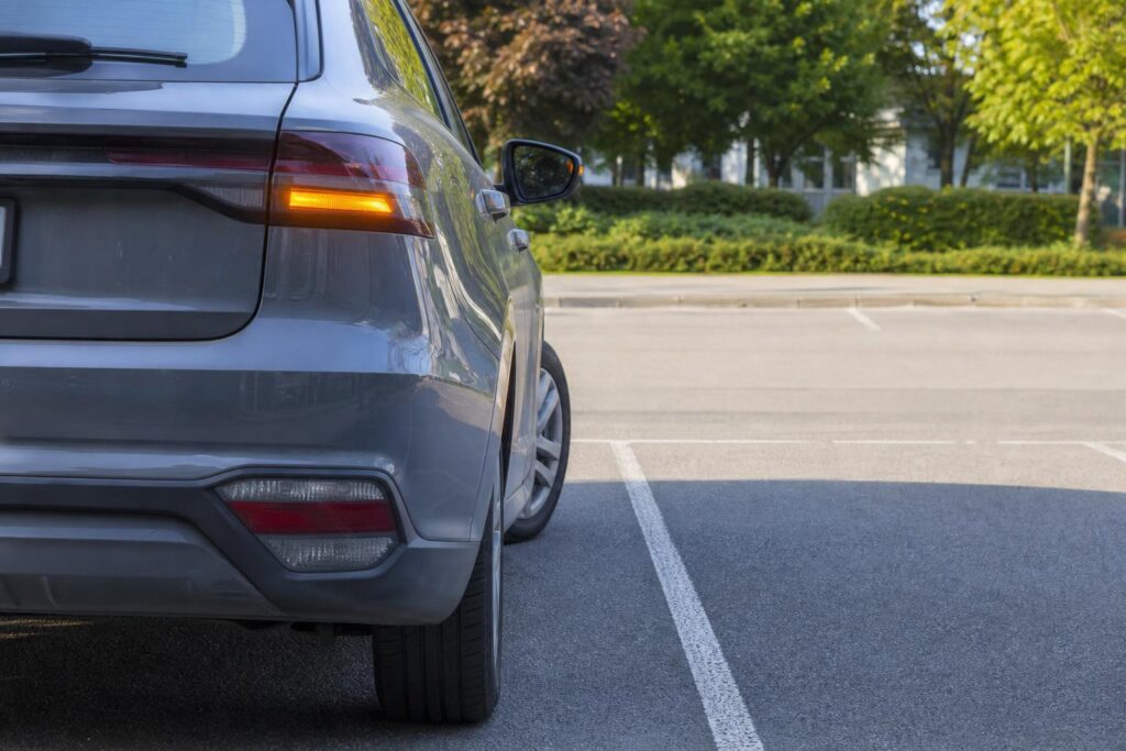 Autó irányjelzővel kitolat egy kijelölt parkolóhelyről