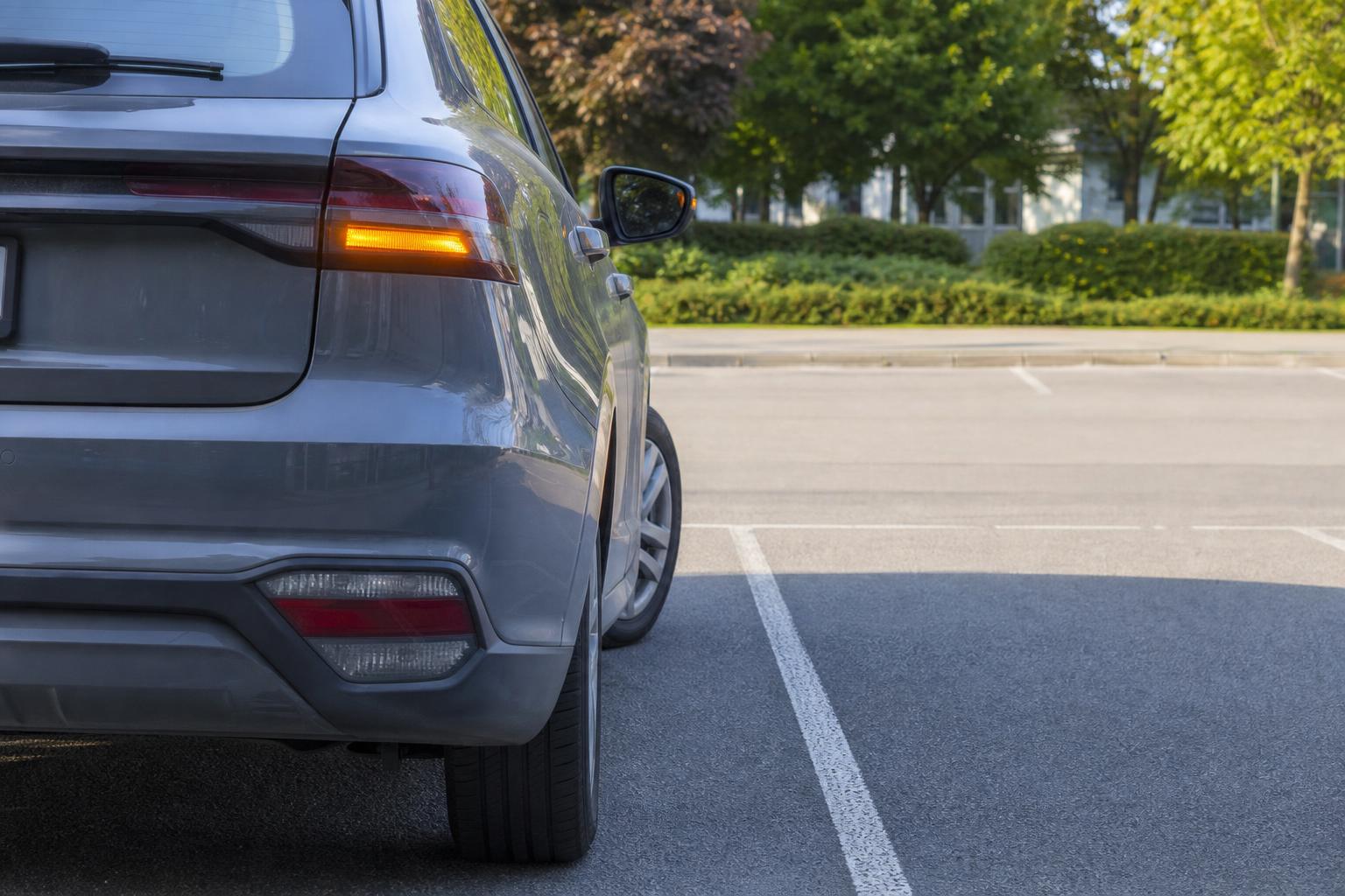 Autó irányjelzővel kitolat egy kijelölt parkolóhelyről