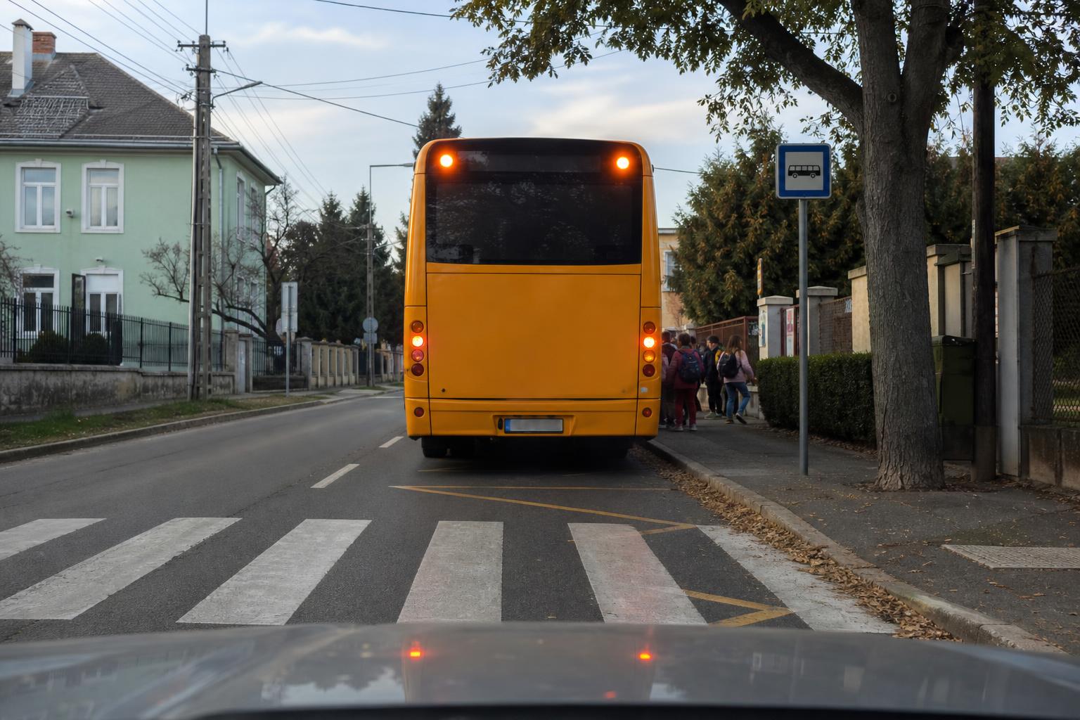 Iskolabusz áll iskola előtti útszakaszon gyalogátkelőhely és gyermekek mellett