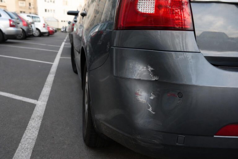 Parkoló autó sérült hátsó lökhárítója ismeretlen károkozó által okozott karcolással és horpadással