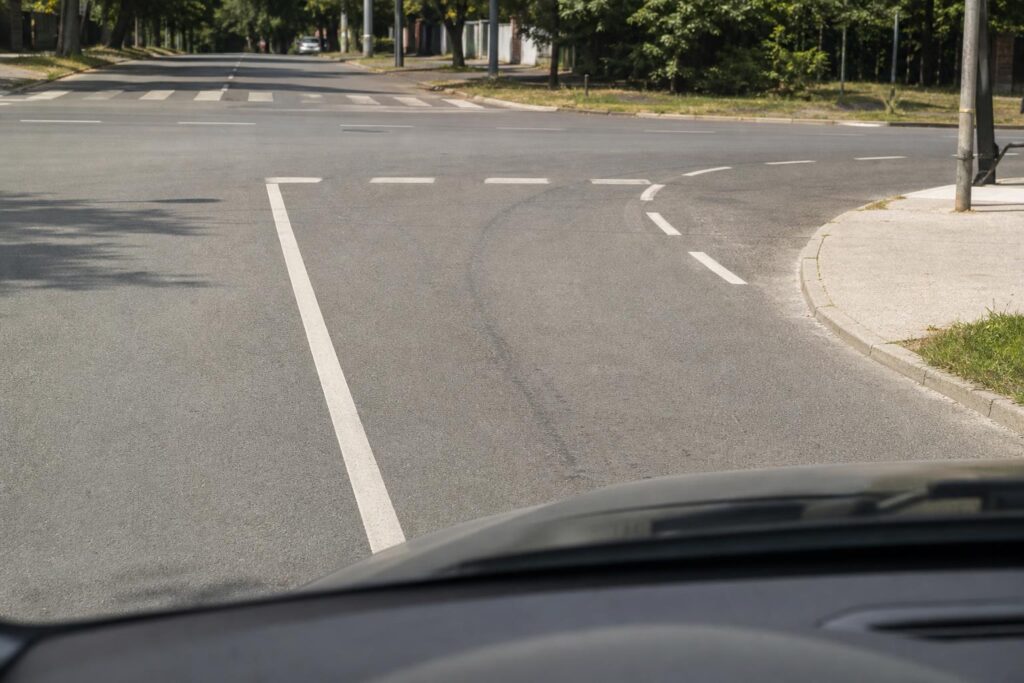 Autó egy útkereszteződésben, amely szabályosan kanyarodás előtt a záróvonal előtt marad