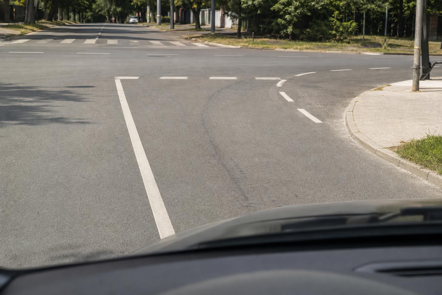 Autó egy útkereszteződésben, amely szabályosan kanyarodás előtt a záróvonal előtt marad