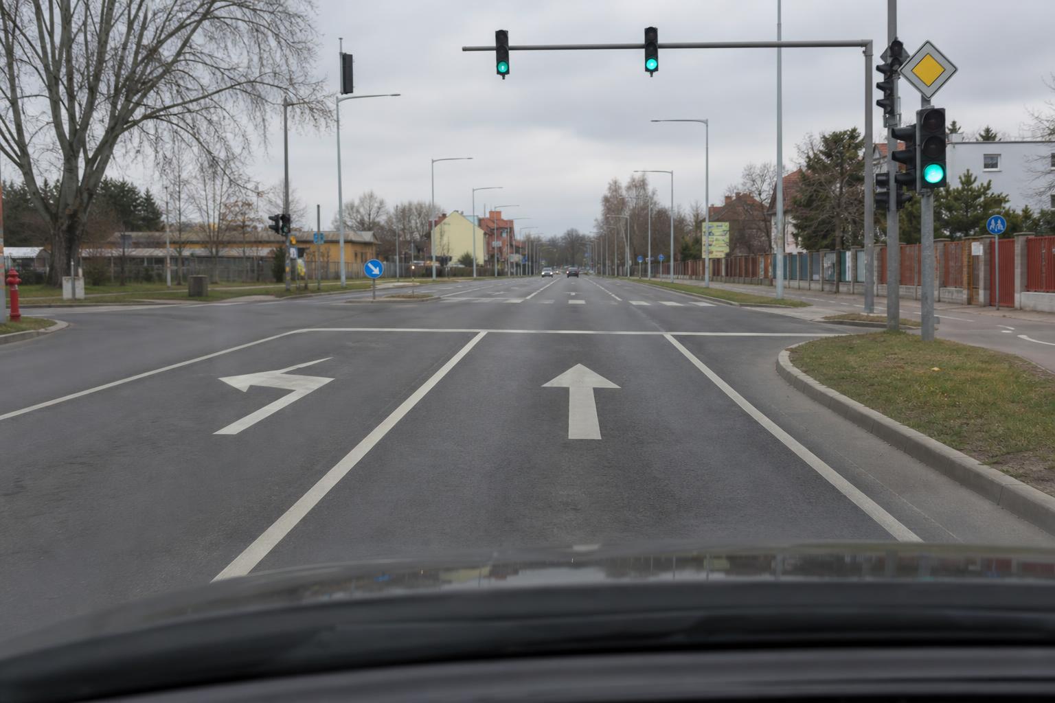 Kereszteződéshez vezető úton látható kanyarodósáv és egyenesen haladó sáv irányjelző nyilakkal