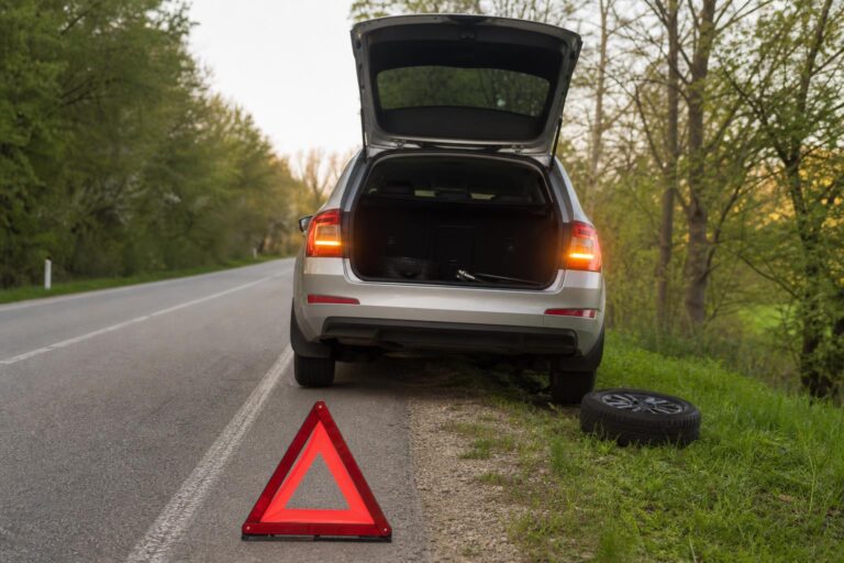 Biztonságosan az út szélén álló defektes autó vészvillogóval és kihelyezett elakadásjelző háromszöggel