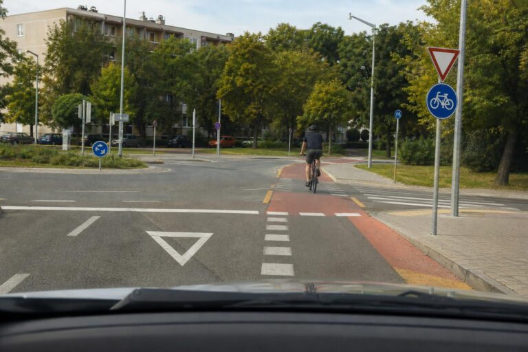 Autó és kerékpáros találkozása egy úttesten átvezető kerékpárútnál