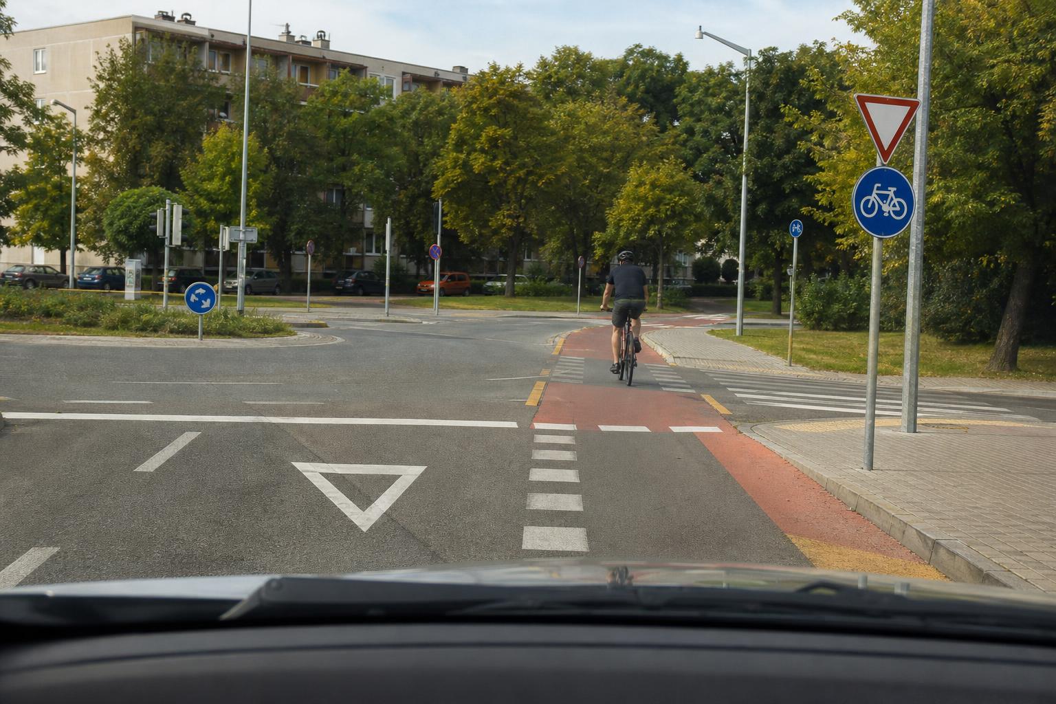 Autó és kerékpáros találkozása egy úttesten átvezető kerékpárútnál