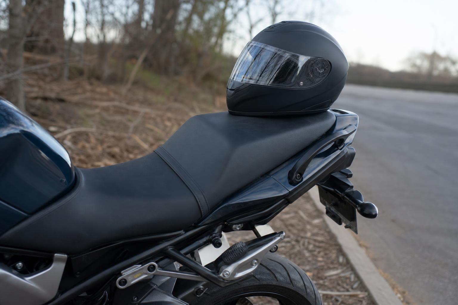 Motorkerékpár hátsó utasüléssel, lábtartóval és kapaszkodószíjjal egy csendes út szélén