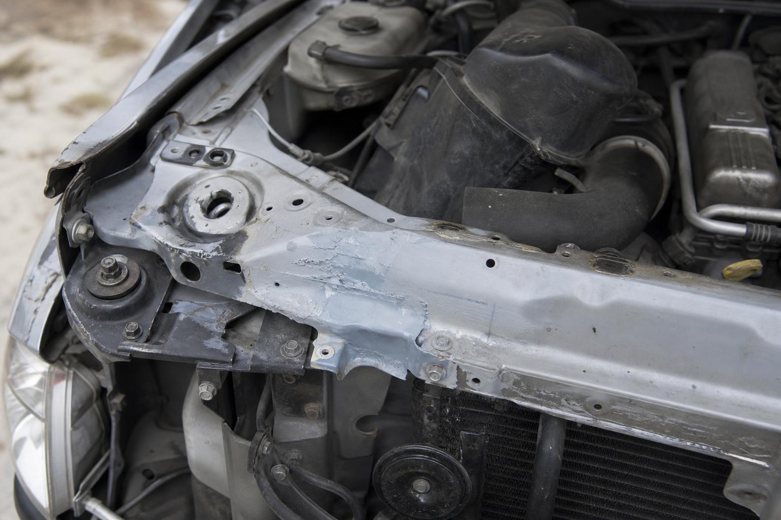 Korábbi törés nyomai egy használt autó motorterében, eltérő festéssel és javított illesztésekkel