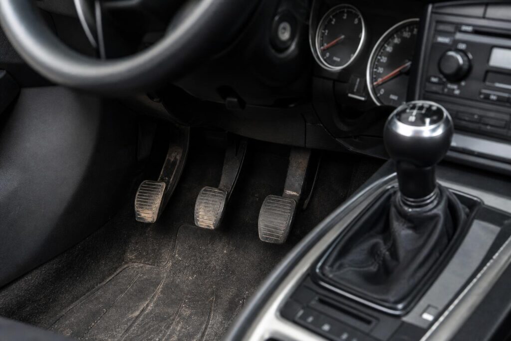 Kézi sebességváltós autó kuplungpedálja és sebességváltója közeli, élethű felvételen