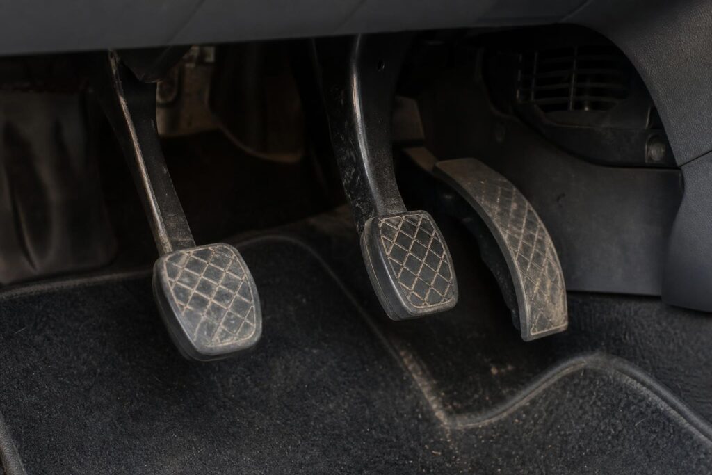 Autó kuplungpedálja a vezetőoldali lábtérben, a nyikorgó működéshez kapcsolódó mechanikus részletekkel