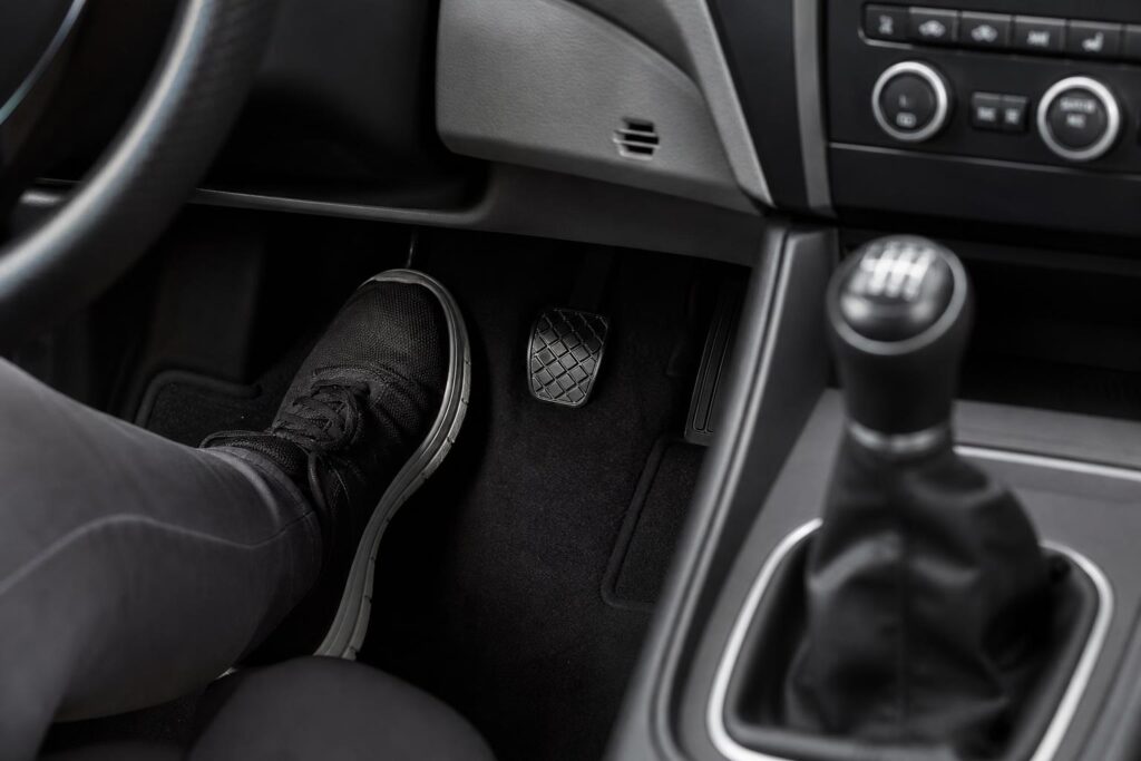 Kézi sebességváltós autó kuplungpedálja és sebességváltója gyakorlás közben