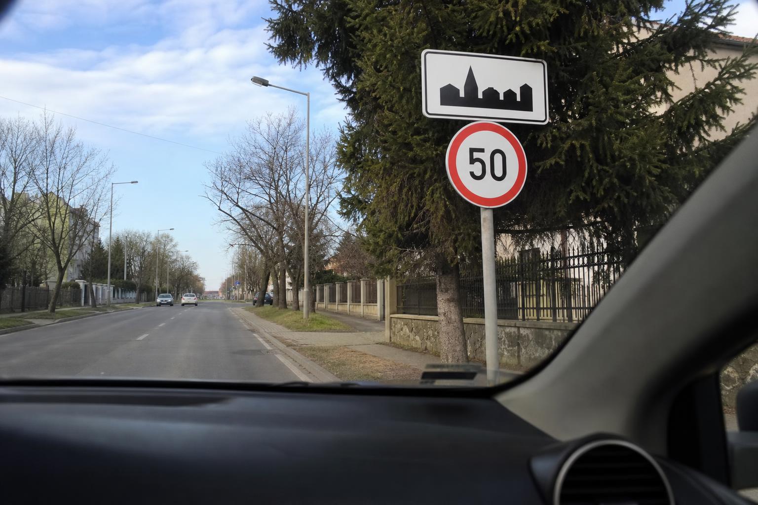 Autó 50 km/h-s sebességkorlátozó tábla felé halad lakott területen