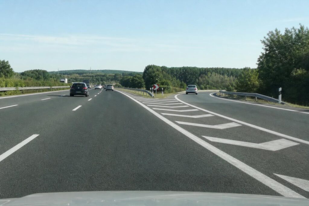 Autópálya jobb oldali lassítósávja egy lehajtó előtt, jól látható burkolati jelekkel és biztonságosan haladó járművekkel