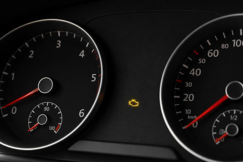 Autó műszerfala közelről világító sárga motorhiba-jelző ikonnal