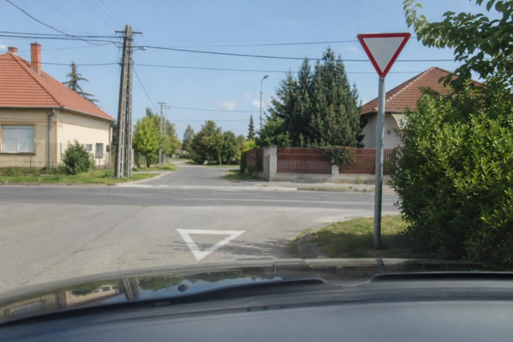 Autó közeledik a macisajt táblával jelzett kereszteződéshez